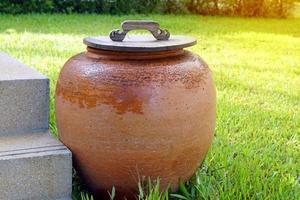 Orangenglas mit Deckel auf dem Gras neben der Zementtreppe zur Gartendekoration. weicher und selektiver Fokus. foto