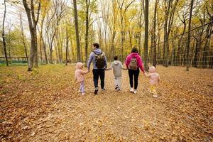 Rückseite der Familie mit Kindern bei einem Spaziergang im Herbstwald. foto