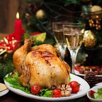 gebackener Truthahn oder Huhn. Der Weihnachtstisch wird mit einem Truthahn serviert, der mit leuchtendem Lametta und Kerzen dekoriert ist. Brathähnchen, Tisch. Weihnachtsessen. foto