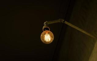 Glühbirne an einer Rohrleitung in einem dunklen Raum foto