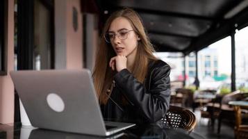 junge Frau, die online am Laptop im Stadtcafé arbeitet foto