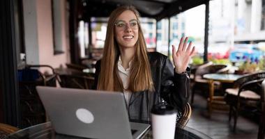 junge Studentin, die online in einem Café auf einem Laptop mit einer Tasse Kaffee arbeitet foto