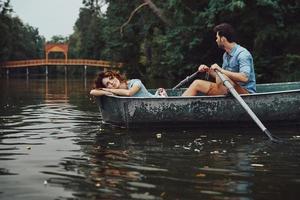 Sommer genießen. Schönes junges Paar lächelt, während es ein romantisches Date auf dem See genießt foto