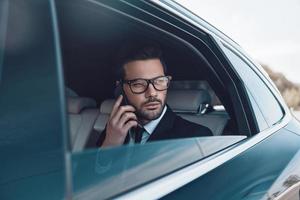 Geschäftsdetails besprechen. nachdenklicher junger geschäftsmann, der am telefon spricht, während er im auto sitzt foto