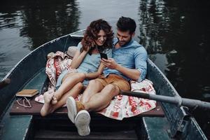 verliebt in Musik. schönes junges Paar, das Musik hört, während es draußen im Boot sitzt foto