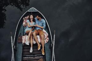 einfach glücklich fühlen. Draufsicht auf ein schönes junges Paar, das sich umarmt und lächelt, während es im Boot liegt foto