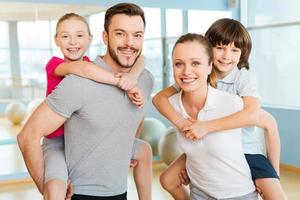 sportliche Familie. glückliche sportliche familie, die sich verbindet, während sie zusammen im sportverein stehen foto