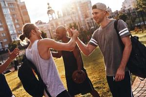 enge Freunde. Gruppe junger Männer in Sportkleidung, die gestikulieren und lächeln, während sie im Freien stehen foto