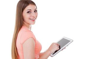 Schönheit mit digitalem Tablet. schöne junge Frau, die digitales Tablet verwendet und über die Schulter schaut, während sie isoliert auf Weiß steht foto
