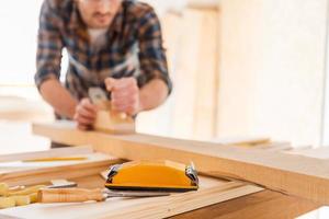 Arbeiten mit Holz. Nahaufnahme eines männlichen Tischlers, der in seiner Werkstatt mit Holz arbeitet foto