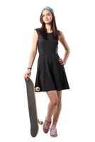 junges Mädchen im schwarzen Kleid steht mit einem Skateboard foto