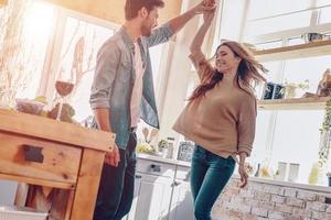 glückliche Momente zusammen. in voller Länge von einem schönen jungen Paar in Freizeitkleidung, das tanzt und lächelt, während es zu Hause in der Küche steht foto