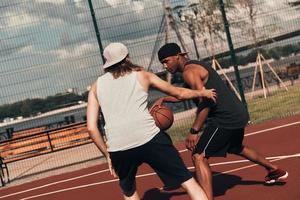 Wettbewerb. Zwei junge Männer in Sportkleidung spielen Basketball und verbringen Zeit im Freien foto