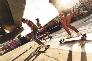 ihr Gleichgewicht halten. Gruppe junger Leute, die Skateboard fahren, während sie draußen im Skatepark abhängen foto