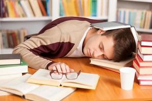 in der Bibliothek schlafen. müder junger mann, der in der bibliothek schläft foto