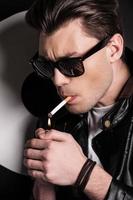eine Zigarette anzünden. hübsches männliches Model in Lederjacke, das sich eine Zigarette anzündet foto