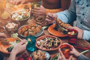 freundliches Abendessen. Blick von oben auf eine Gruppe von Menschen, die zusammen zu Abend essen, während sie am rustikalen Holztisch sitzen foto