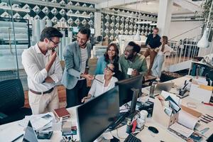 Gruppe junger moderner Menschen in eleganter Freizeitkleidung, die während der Arbeit im Büro über Geschäfte diskutieren foto