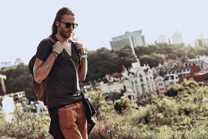 der richtige Ort zum Nachdenken. hübscher junger Mann in Freizeitkleidung, der draußen auf dem Hügel spaziert, während er seine Reise genießt foto