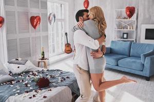 endlose Liebe. Schönes junges Paar, das sich umarmt und lächelt, während es im Schlafzimmer voller Luftballons steht foto