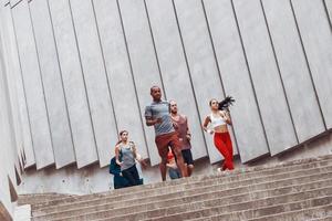 Gruppe junger Menschen in Sportkleidung beim Joggen auf der Treppe im Freien foto