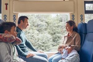 familie mit zwei kleinen kindern, die zusammen zugfahrt genießen foto