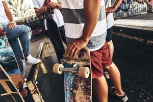 bereit zum Schlittschuhlaufen. Nahaufnahme junger moderner Menschen, die mit Skateboards stehen, während sie Zeit im Freien verbringen foto
