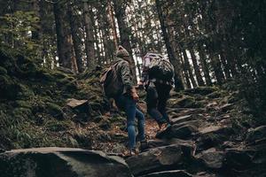 die Natur erkunden. Rückansicht in voller Länge eines jungen Paares, das sich beim gemeinsamen Wandern im Wald nach oben bewegt foto