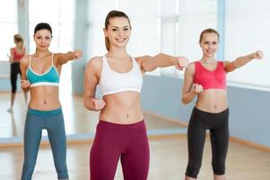 Frauen trainieren. Drei schöne junge Frauen in Sportkleidung trainieren und schauen in die Kamera foto