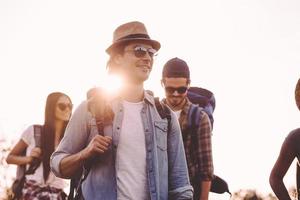 Freunde wandern. gruppe junger leute mit rucksäcken, die zusammen gehen und glücklich aussehen foto