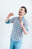 Glück ohne Grenzen. fröhlicher junger Mann im Hemd gestikuliert und lächelt, während er vor weißem Hintergrund steht foto