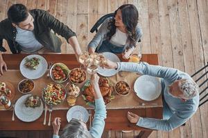 Draufsicht einer Familie mit mehreren Generationen, die beim gemeinsamen Abendessen anstößt foto