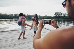 Schöne junge Paare, die unbeschwerte Zeit verbringen, während sie auf dem Pier stehen foto