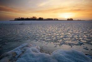 schöne Winterlandschaft mit gefrorenem See und Sonnenunterganghimmel. foto