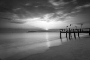 Langzeitbelichtung von magischem Sonnenaufgang und hölzernem Pier foto