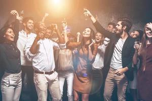 Genießen Sie die beste Party mit Freunden. Gruppe schöner junger Leute, die zusammen tanzen und glücklich aussehen foto