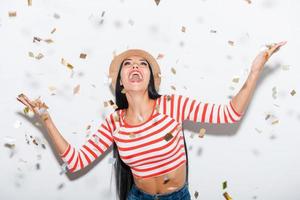 Partyzeit fröhliche junge Frau, die ihre Hände ausstreckt, während Konfetti auf sie fällt foto