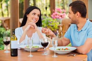 genieße jede Minute in seiner Nähe. schönes junges liebevolles Paar, das spricht und lächelt, während es sich gemeinsam im Restaurant im Freien entspannt foto