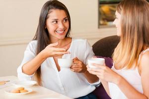 wir verbringen gerne Zeit miteinander. zwei schöne junge frauen, die kaffee trinken und sich unterhalten, während sie zusammen im café sitzen foto