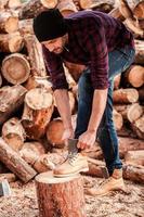 bereiten sich auf die Arbeit vor. voller Länge des selbstbewussten jungen Försters, der seine Schuhe anpasst, während er sich an den Baumstamm lehnt foto