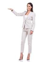 Größe zeigen. volle Länge der überzeugten jungen Geschäftsfrau im Anzug, der Größe beim Stehen gegen weißen Hintergrund zeigt foto