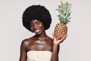 Porträt einer schönen jungen Afrikanerin, die Ananas hält und lächelt foto