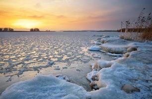 schöne Winterlandschaft mit gefrorenem See und Sonnenunterganghimmel. foto