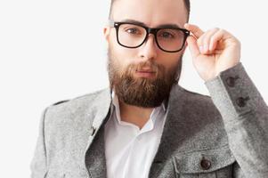 überzeugt von seinem Aussehen. hübscher junger bärtiger mann mit brille, der in die kamera schaut foto