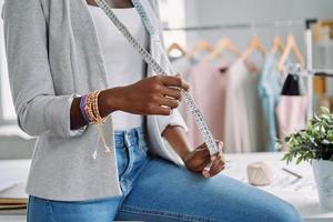 nahaufnahme einer afrikanischen frau, die maßband trägt, während sie im designstudio arbeitet foto