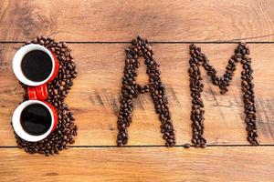 Beginnen Sie Ihren Morgen mit frischem Kaffee. Draufsicht auf Zahlen und Buchstaben aus Kaffeebohnen, die auf dem Holzschreibtisch liegen foto