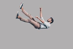Mann fällt hin. Luftaufnahme eines hübschen jungen Mannes, der vor grauem Hintergrund fällt foto