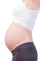 Schwangerschaftsbauch. Seitenansicht Zugeschnittenes Bild einer schwangeren Frau, die isoliert auf Weiß steht foto