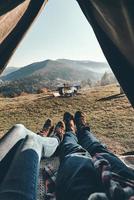 Reisen mit Geliebten. Nahaufnahme eines jungen Paares, das die Aussicht auf die Bergkette genießt, während es im Zelt liegt foto