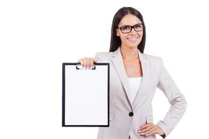 Kopieren Sie Platz in ihrer Zwischenablage. Geschäftsfrau demonstriert leeres Papier auf einem Klemmbrett im Stehen vor weißem Hintergrund foto